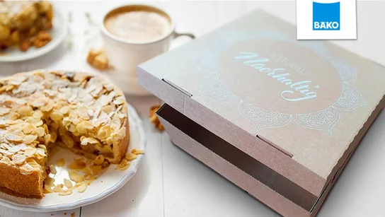 Torten­verpackung für die BÄKO, daneben ein Kaffee und ein Kuchen
