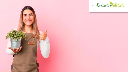 Eine Frau mit einer Pflanze in ihrer linken Hand vor einem rosa Hintergrund